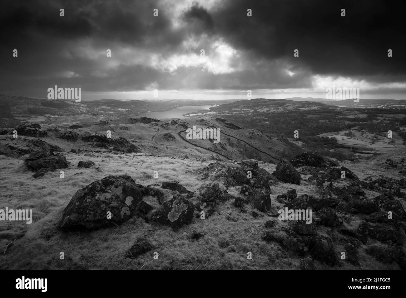 A black and white image of Loughrigg Fell with lake Windermere beyond ...
