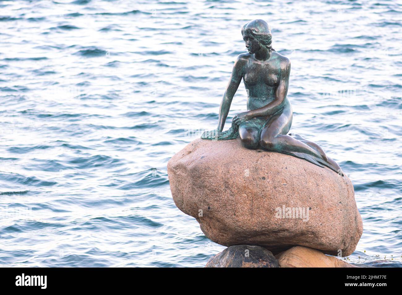 Bronze statue or sculpture of The Little Mermaid displayed on a rock by ...