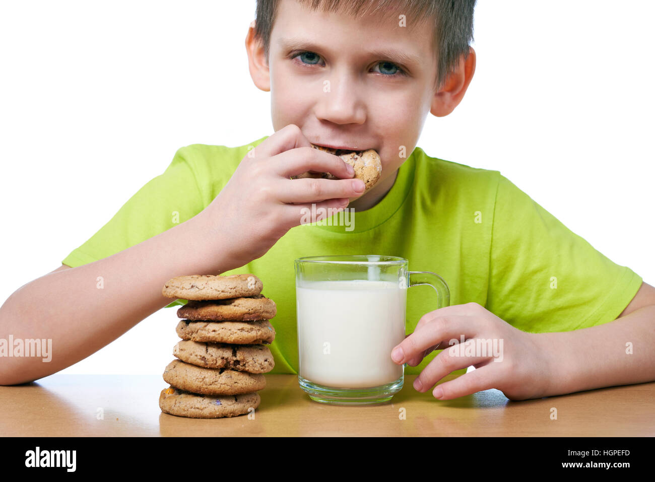 Little boy has breakfast cookies and milk isolated white Stock Photo