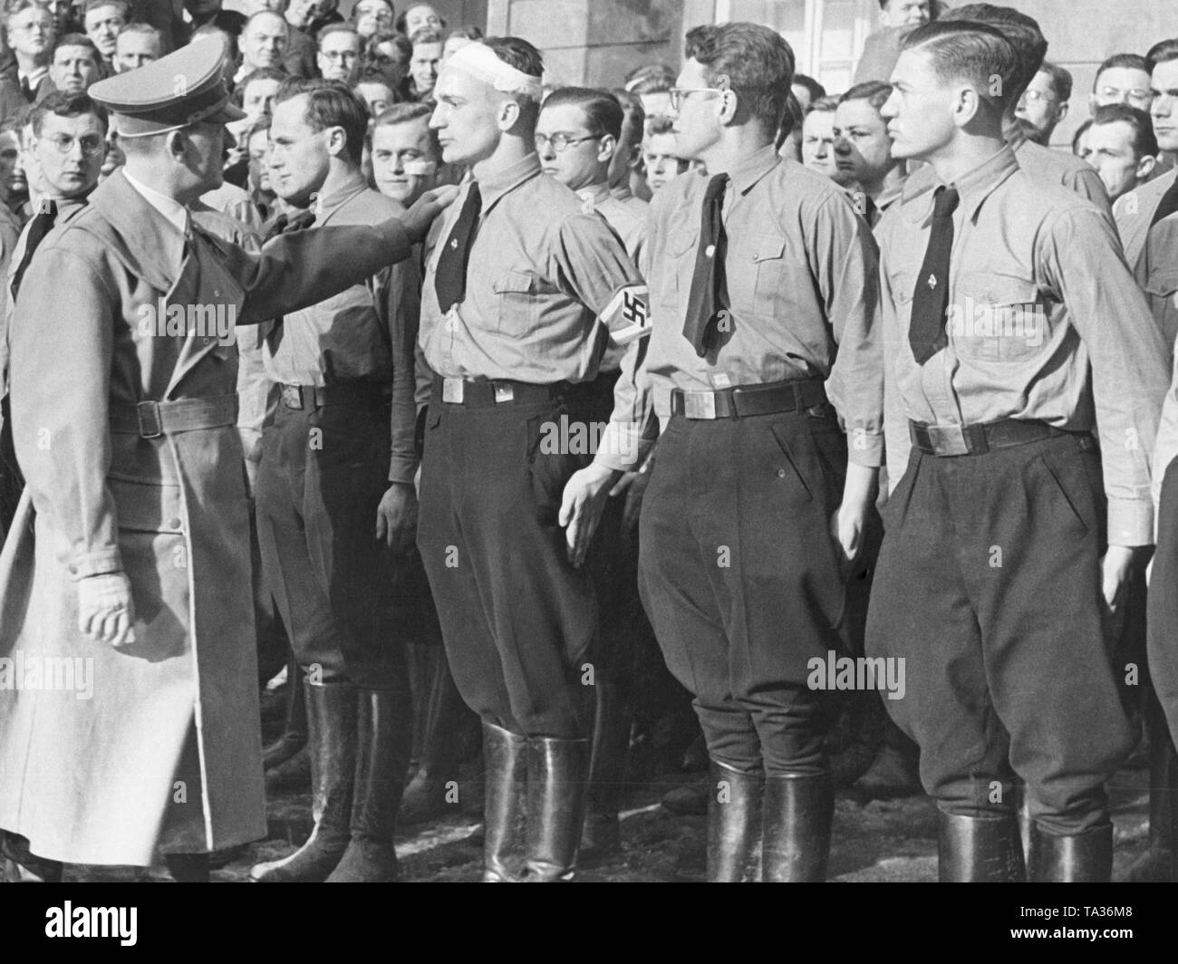 Adolf Hitler in the occupied Sudetenland, 1938. He talks to members of the  Hitler Youth. His hand is laid on the shoulder of a young man with a head  bandage Stock Photo -